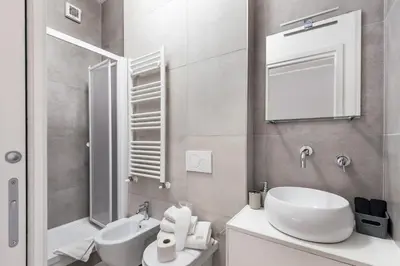 a white bathroom with a sink and a mirror at Porta Furba Apartment in Rome