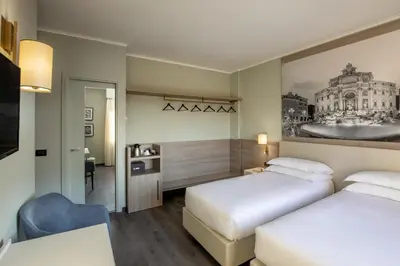 a hotel room with two beds and a desk at Hotel Marc'Aurelio in Rome