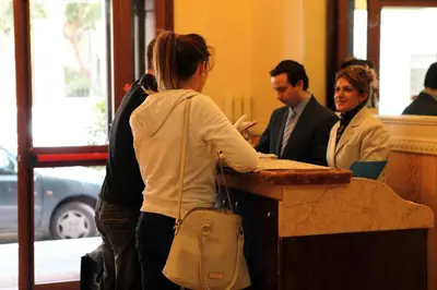 a woman standing at a counter talking to people at Hotel Hollywood in Rome