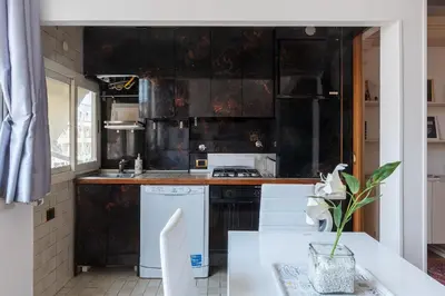 a kitchen with black walls and white appliances at Along the Tiber Apartment in Rome