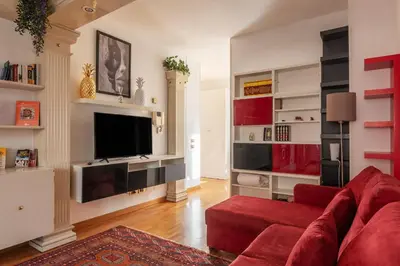 a living room with a red couch and a tv at Along the Tiber Apartment in Rome