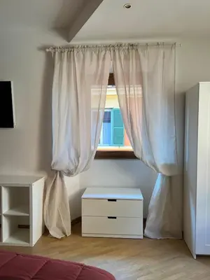 a bedroom with a window with curtains and a dresser at Bella Trastevere in Rome