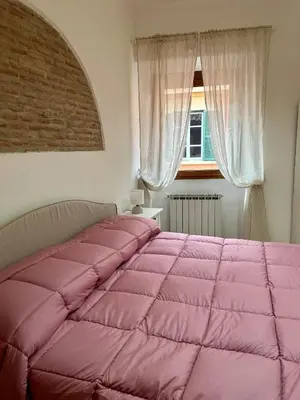 a pink bed in a bedroom with a window at Bella Trastevere in Rome