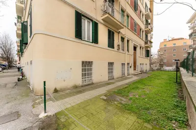 a building with green shuttered windows and a yard at Maroon Flat Colosseo, 800 mt from Amphitheater in Rome