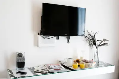a glass shelf with a tv on a wall with drinks at Rome Key Luxury House in Rome