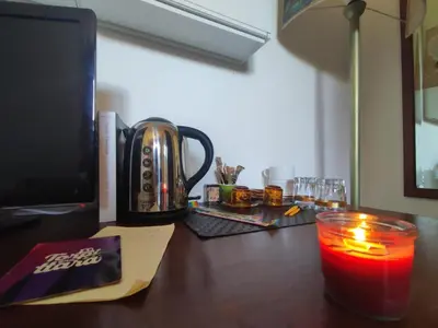 a desk with a candle and a cup on a table with a computer at Parrot Room - Camera a Roma con bagno privato in Rome