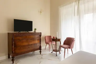 a living room with a tv on a dresser and chairs at Casa Gold by Hili in Rome