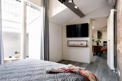 a bedroom with a bed and a tv on a wall at Idyllia - Borgognona luxury home in Rome