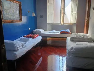 a room with three beds and a window at Arneil Rooms Rome in Rome