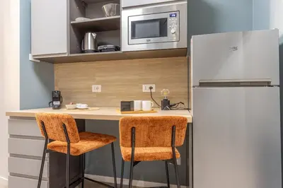 a kitchen with a counter with two chairs and a refrigerator at BDC - Roman Lounge 3BDR at Vatican in Rome