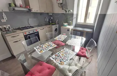 a kitchen with a glass table with red chairs at Tra i Musei Vaticani House in Rome