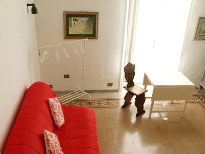a living room with a red couch and a piano at Tra i Musei Vaticani House in Rome