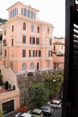 a large pink building with cars parked in front of it at Tra i Musei Vaticani House in Rome