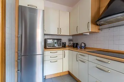 a kitchen with white cabinets and a stainless steel refrigerator at iFlat The Roman House - Spacious & Central Apt in Rome