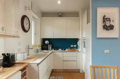 a kitchen with white cabinets and a clock on the wall at Terrazza d'autore in Rome