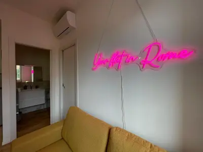 a living room with a couch and a neon sign at Metro Marconi - University quarter apartments in Rome
