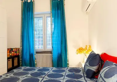a bedroom with blue curtains and a bed and a window at Plumeria Bianca in Rome
