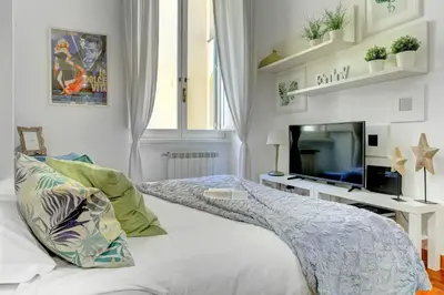a white bedroom with a bed and a tv at Colosseo - MecenStudio - Home and More in Rome