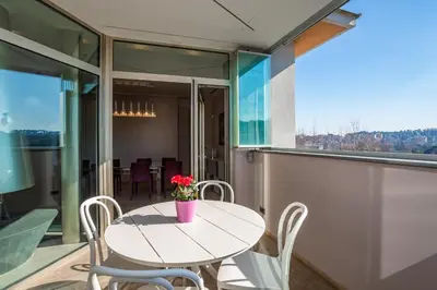 a white table with chairs and a vase of flowers on a balcony at Vatican Exclusive Penthouse w Terrace and Parking in Rome