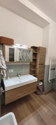 a bathroom with a large white sink and wooden cabinets at A casa di Fede b&b in Rome