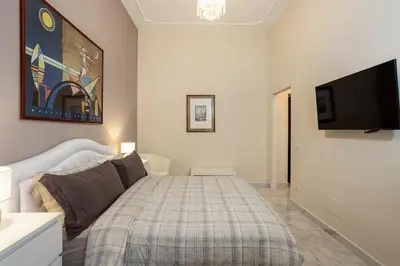 a bedroom with a bed and a flat screen tv at Domus Vespignani in Metro Lodi e San Giovanni - The Bright Spot in Rome