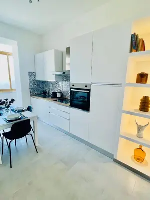 a kitchen with white cabinets and a dining table at Palmira house in Rome