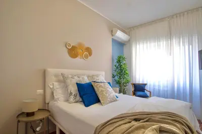 a bedroom with a white bed with blue pillows at Grazia Appartamento Moderno & Chic a Tiburtina in Rome
