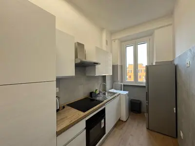 a kitchen with white cabinets and a stainless steel refrigerator at Urban Retreat Steps from the Metro in Rome