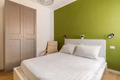 a bedroom with a white bed and a green wall at Design Apartment, near Tiburtina Station in Rome