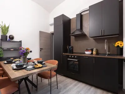 a kitchen with black cabinets and a wooden table at The Best Rent - Modern One-Bedroom Apartment in Trastevere in Rome