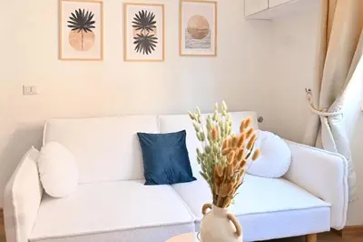 a living room with a white couch with a blue pillow at Cozy Studio Steps from Metro station in Rome