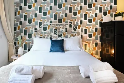 a bedroom with a large white bed with a wall at Cozy Studio Steps from Metro station in Rome