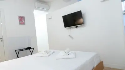 a room with two white beds and a tv on the wall at Aria Charme in Rome