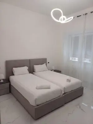 a white bedroom with a large bed with a chandelier at 612 Flats in Rome