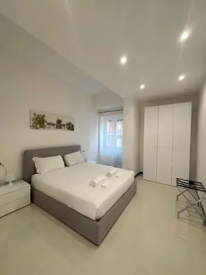 a white bedroom with a large bed and a cabinet at 612 Flats in Rome