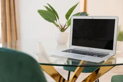 a laptop on a glass table with a potted plant at Piazza Cavour Apartment 90 in Rome