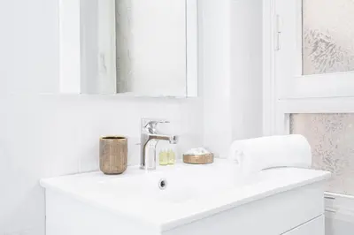 a white bathroom with a sink and a mirror at Piazza Cavour Apartment 90 in Rome