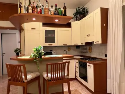 a kitchen with white cabinets and a counter with two chairs at ARTPA Rome Apartments Gianicolo, Roma in Rome