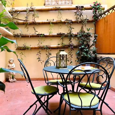 a patio table and chairs with plants on a wall at Il patio al Colosseo in Rome