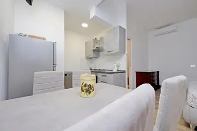 a white kitchen with a table with a vase on it at Monica's house in Rome