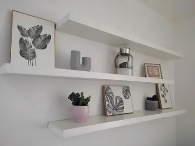 a white shelf with pictures and a plant on it at Benny's House Rome in Rome