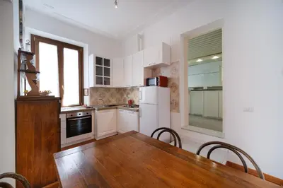 a kitchen with a wooden table and a white refrigerator at Terrazza Monteverde by BuddyRent in Rome