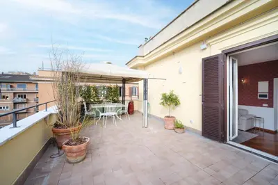 a balcony with a table and chairs and an umbrella at Terrazza Monteverde by BuddyRent in Rome