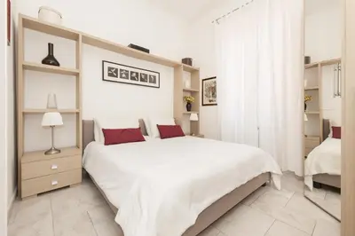 a white bedroom with a large white bed with red pillows at Foscolo al 24 in Rome