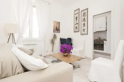 a white living room with white furniture and purple flowers at Foscolo al 24 in Rome