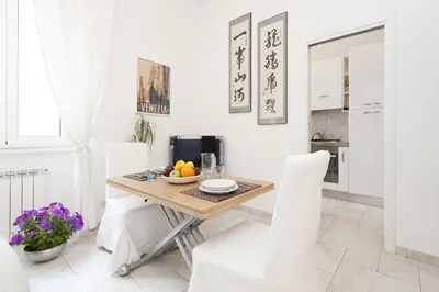 a white dining room with a wooden table and white chairs at Foscolo al 24 in Rome