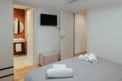 a white bedroom with a bed with a tv on the wall at Marino's Apartment in Rome