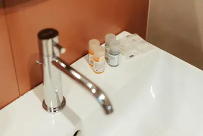 a bathroom sink with a faucet and two bottles on it at Marino's Apartment in Rome
