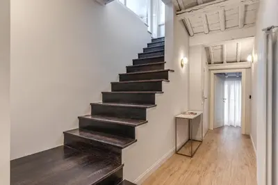 a staircase with black treads in a white room with wood floors at Maison Della Vite in Rome