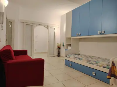 a living room with a bed and a red chair at Regina di Cuori in Rome
